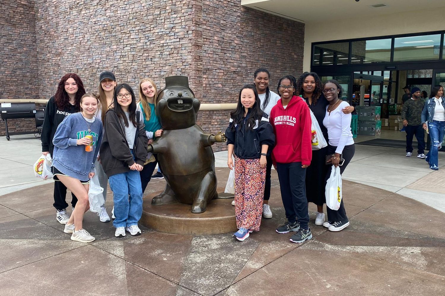 Students posing with a statue of an animal